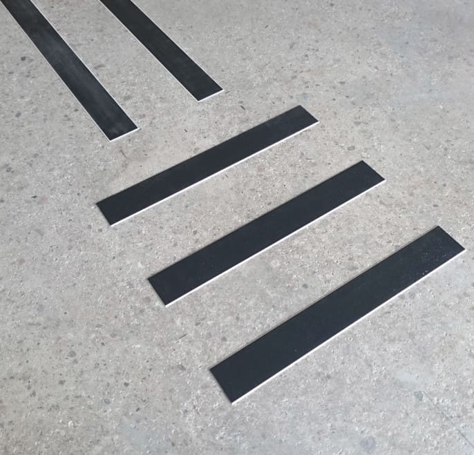 Närbild på svarta ledstråk av materialet akryl. Ledstråkets kant är fasat och har en ljus ton.