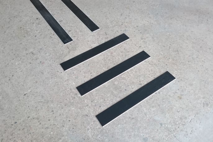 Närbild på svarta ledstråk av materialet akryl. Ledstråkets kant är fasat och har en ljus ton.