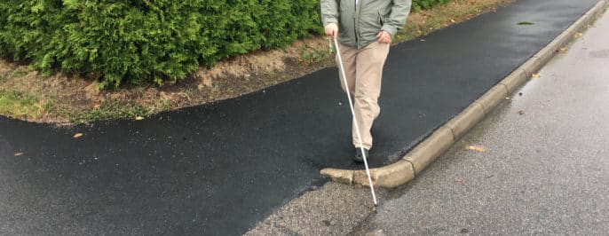 Fredrik navigerar med käpp och följer trottoaren fram till korsning där kanten tar slut.