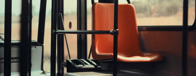 Bilden symboliserar "att resa till jobbet" och visar ett orange passagerarsäte i en buss.